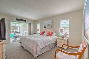 A bedroom with a large bed, a nightstand, a chair, and a view of a pool through the sliding glass door. - Waterfront Home w/ Dock, Kayaks, Pool + More! (Crystal River)