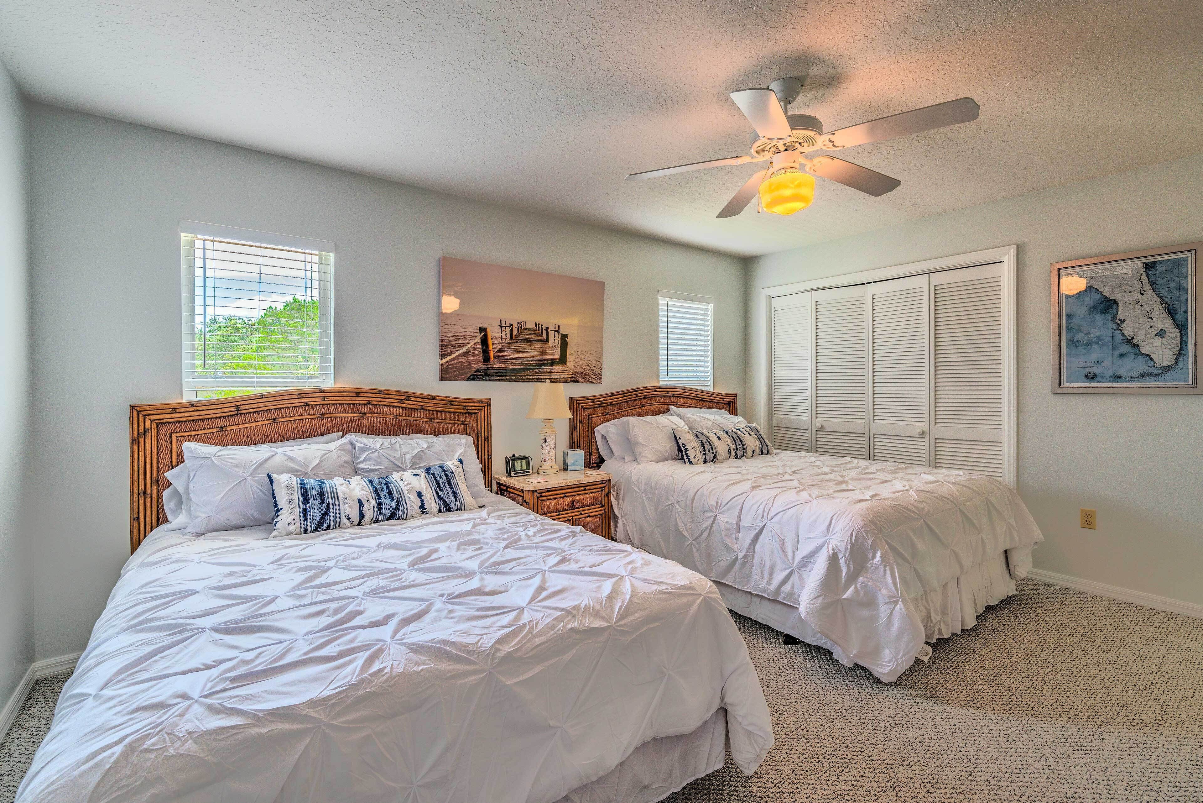 A bedroom with two beds, a ceiling fan, and a window with blinds.