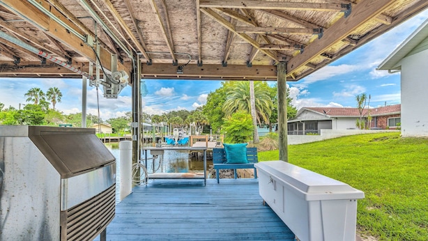 A covered outdoor area with a grill, seating, and a view of a marina. - Waterfront Home w/ Dock, Kayaks, Pool + More! (Crystal River)