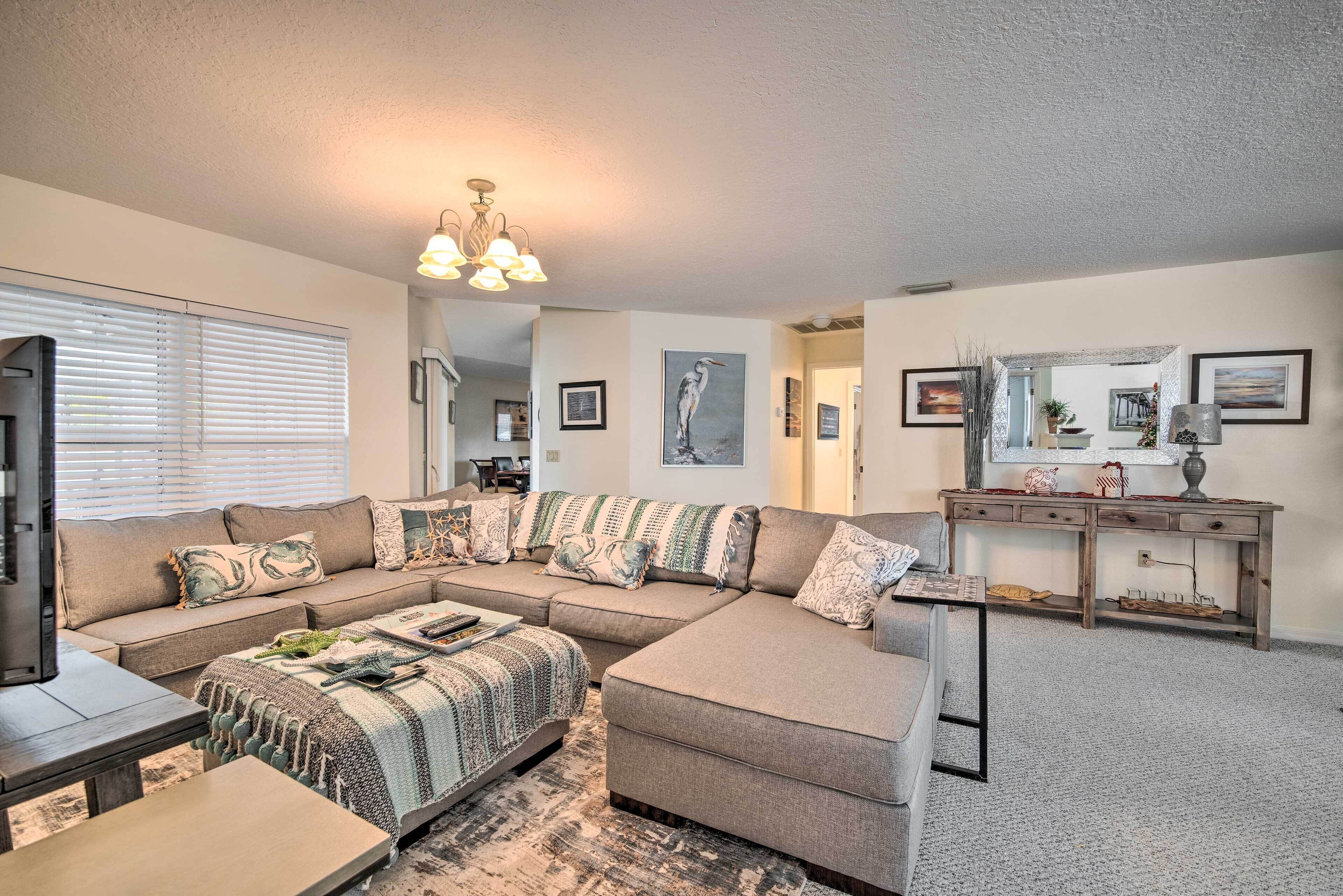 A living room with a sectional sofa, a coffee table, and a desk with a lamp.