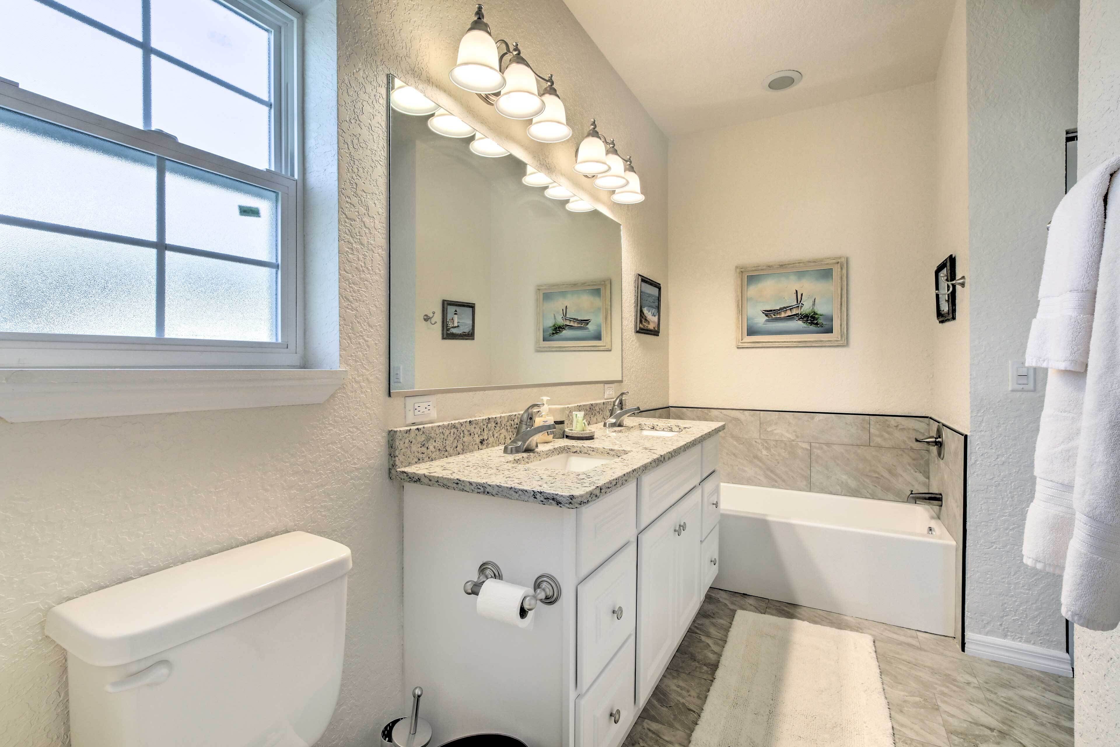 A bathroom with a toilet, double sink vanity, and bathtub.