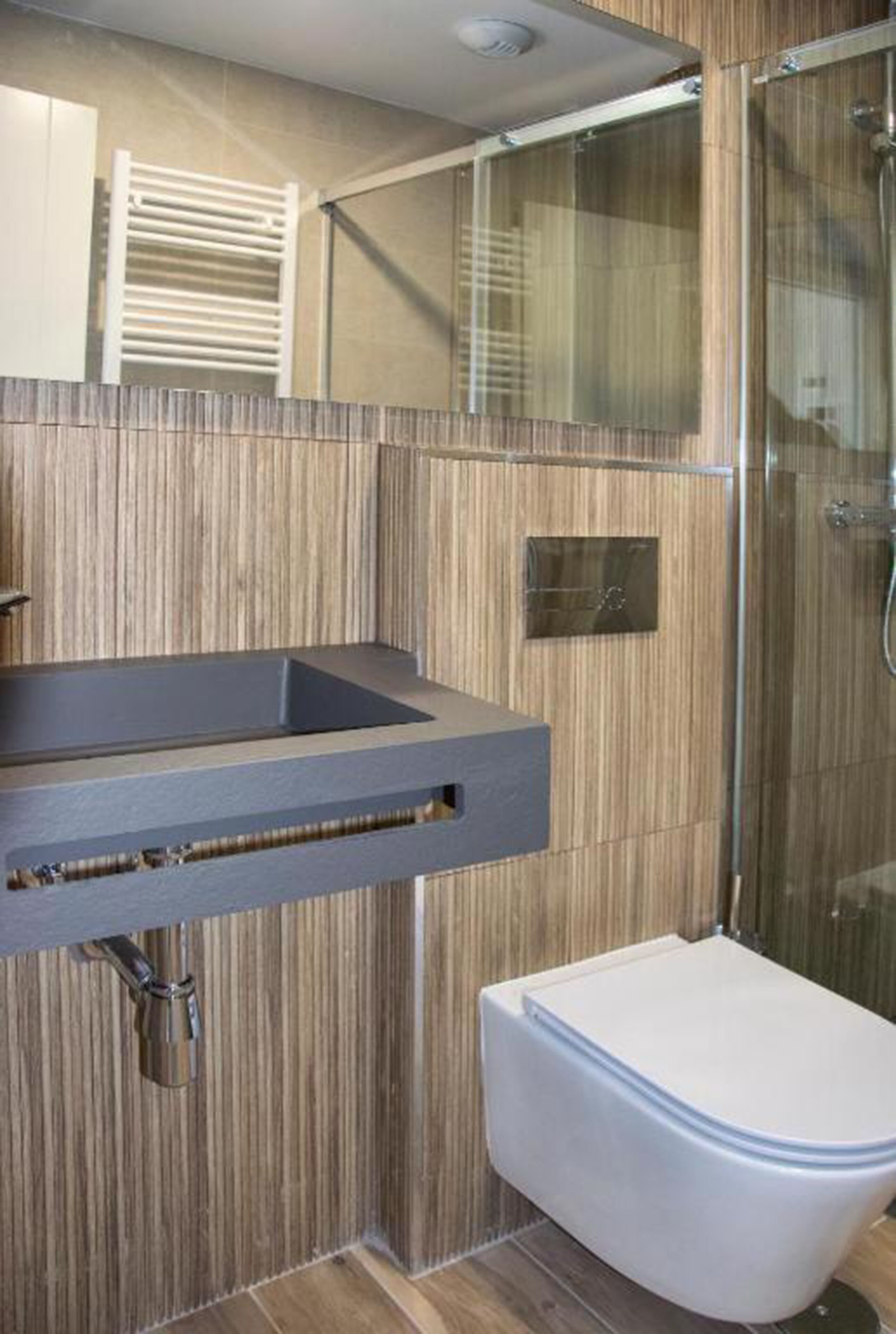 Une salle de bain moderne avec un mur recouvert de panneaux en bois, un lavabo intégré et une cabine de douche en verre.