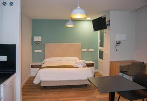 Ein Hotelzimmer mit einem Bett, Nachttischen, einem Schreibtisch mit Stuhl, einem Fernseher und einem Fenster.