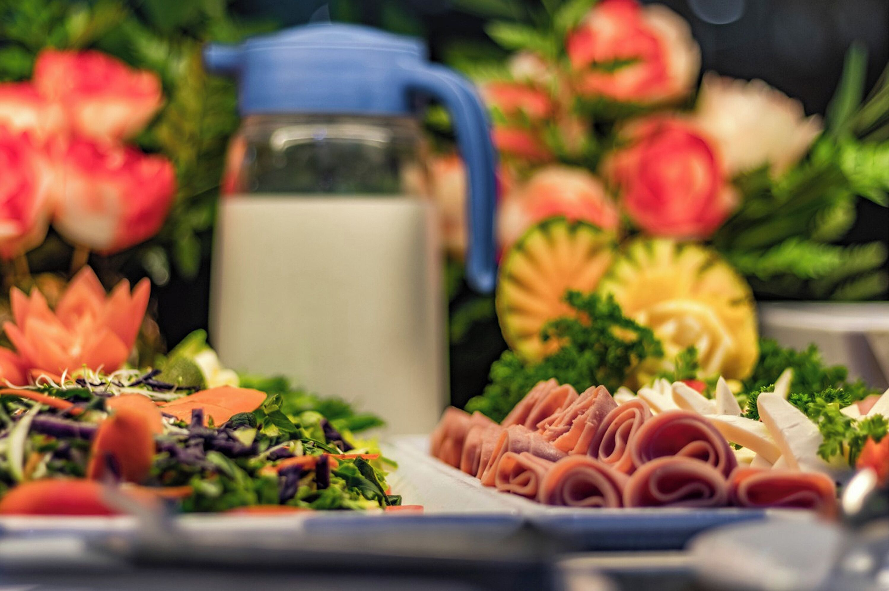 A table with various food items, including a pitcher of milk, a salad, and sliced meats.
