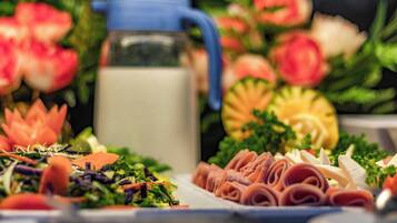 A table with various food items, including a pitcher of milk, a salad, and sliced meats.