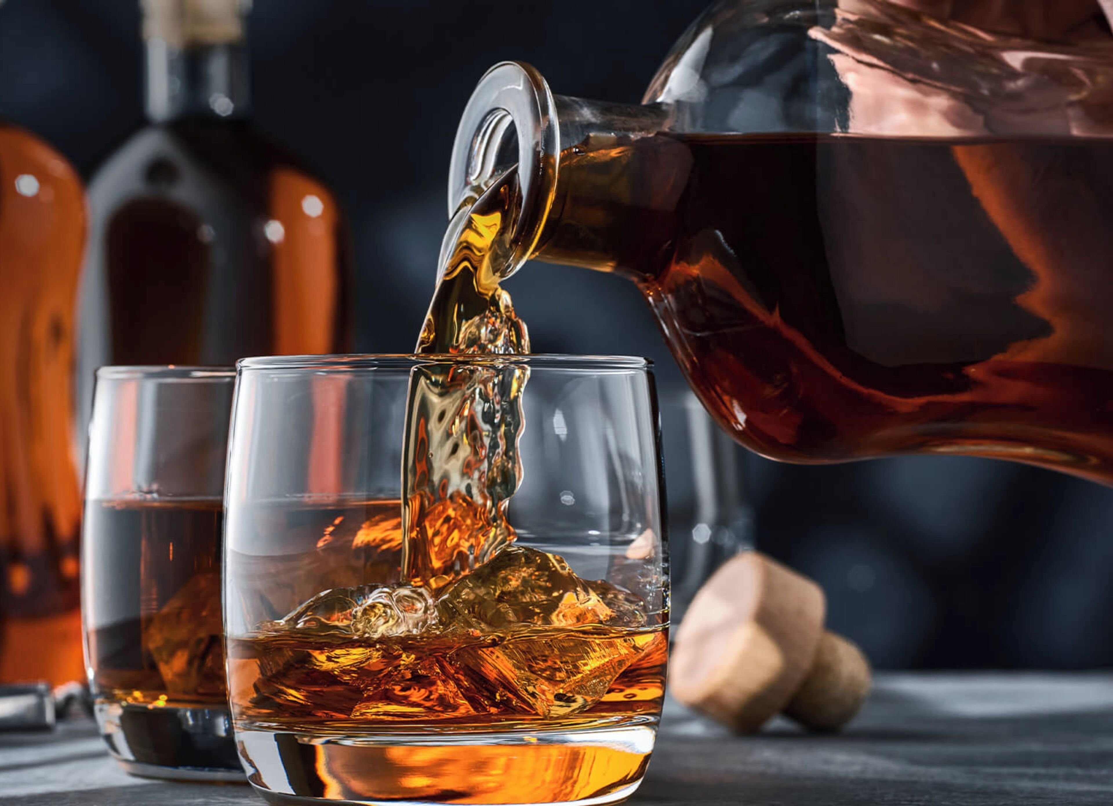 A copper teapot pouring amber-colored liquid into a glass.