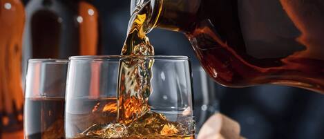 A copper teapot pouring amber-colored liquid into a glass.