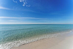 Een strand met helder water, een zandstrand en een strakblauwe lucht.
