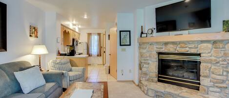 A living room with a stone fireplace, a flat-screen TV, a sofa, and a coffee table.