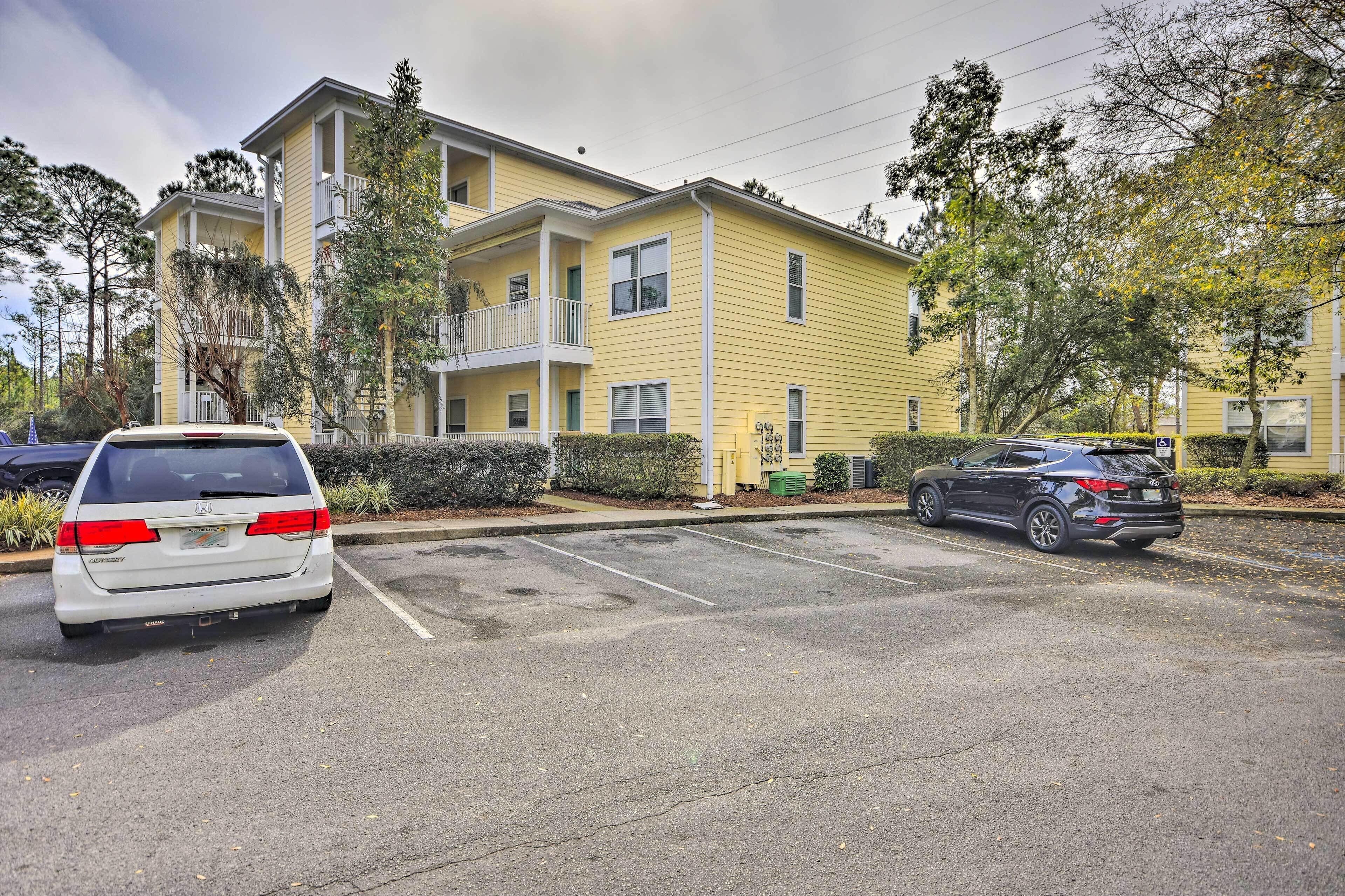 A multi-story yellow building with a parking lot in front.