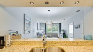 Une cuisine dotée d’un évier à deux bacs, d’un plan de travail en granit et d’un luminaire suspendu.