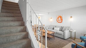 A staircase leading to a living area with a sofa, coffee table, and a small side table. - Oceanfront Daytona Beach Condo w/ Beach Views! (Daytona Beach)