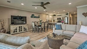 A spacious living room with a television, dining area, and kitchen in the background. - Beachy Lakefront Escape - Walk to the Shore! (Miramar Beach)
