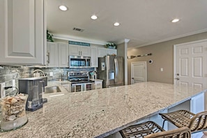 A kitchen with white cabinets, stainless steel appliances, and a granite countertop. - Beachy Lakefront Escape - Walk to the Shore! (Miramar Beach)