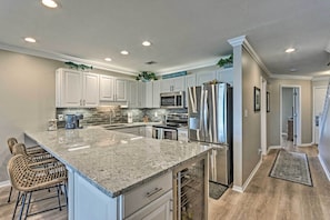 A modern kitchen with white cabinets, stainless steel appliances, and a granite countertop. - Beachy Lakefront Escape - Walk to the Shore! (Miramar Beach)