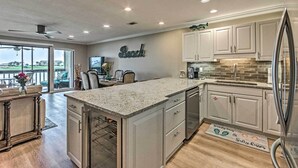 A modern kitchen with white cabinets, a granite countertop, and a stainless steel refrigerator. - Beachy Lakefront Escape - Walk to the Shore! (Miramar Beach)