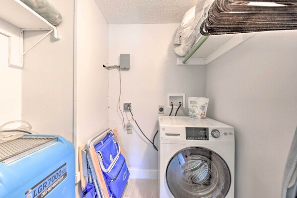 A laundry room with a front-loading washing machine, a blue dehumidifier, and a wall-mounted heater. - Walk to Beach: Condo w/ Pool & Patio In Sarasota! (Siesta Key)