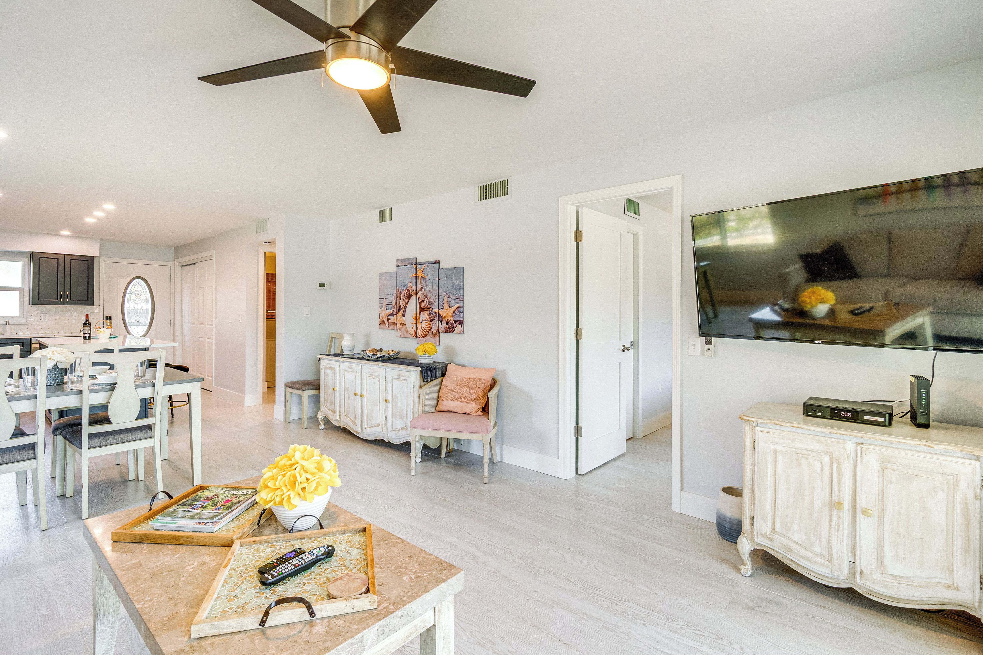 A spacious living area with a dining table, kitchen, and a large flat-screen TV mounted on the wall.