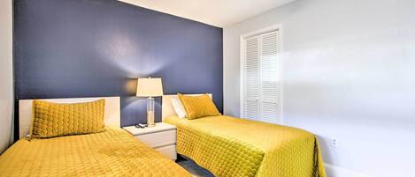 A bedroom with two beds, a nightstand, a lamp, and a ceiling fan.