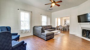 Un salon spacieux avec un canapé d’angle, un ventilateur de plafond et une cheminée.