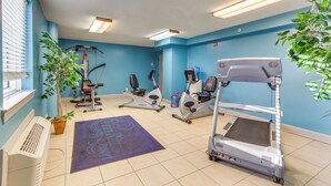 Une salle de sport équipée de matériel d’exercice, d’un tapis de course et d’un mur bleu.