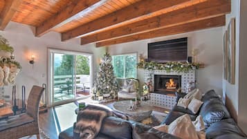 Una sala acogedora con chimenea, sofá de cuero y un árbol de Navidad.