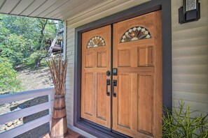 Puerta doble de madera con paneles de vidrio y un picaporte, en una casa con porche.