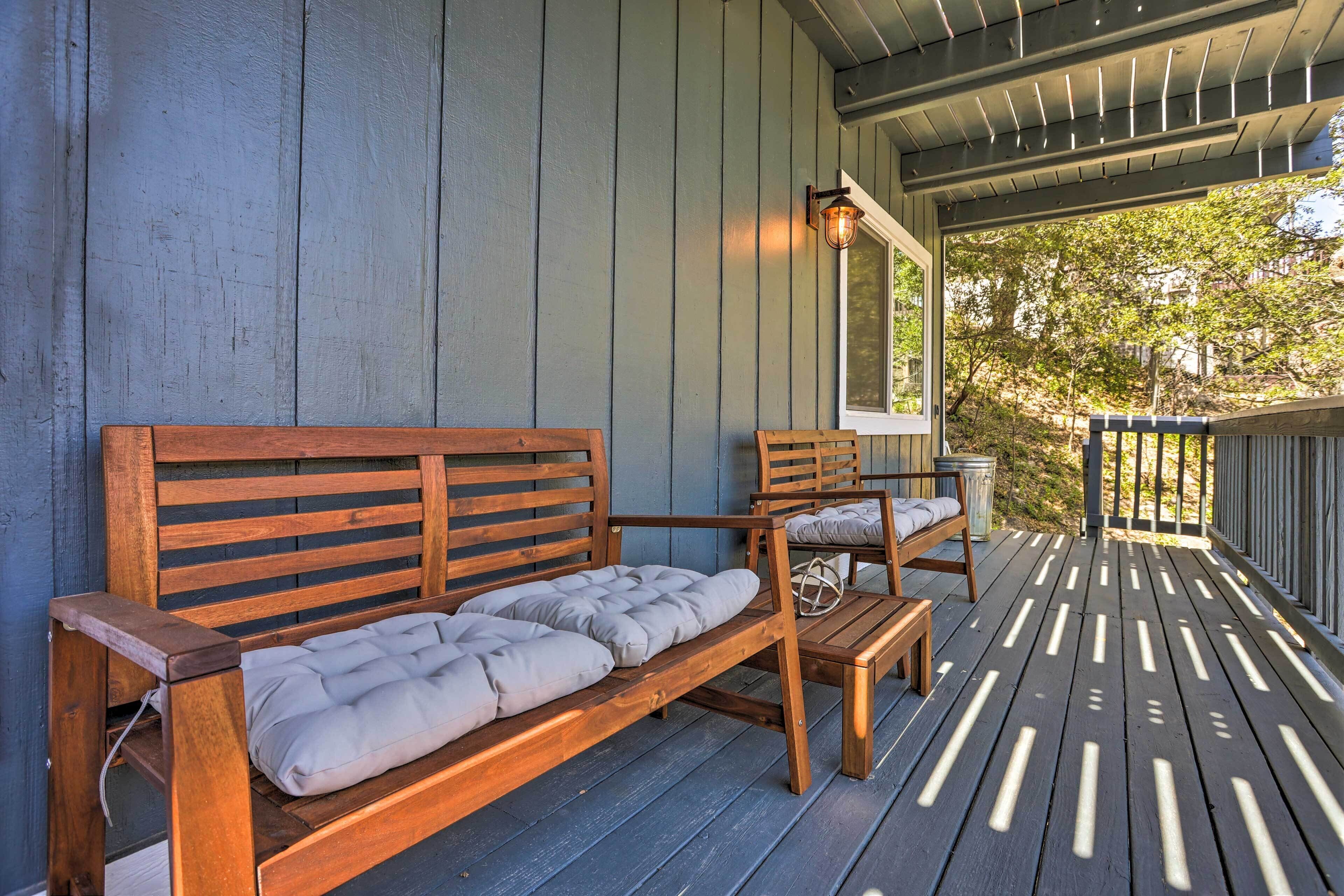 A wooden deck with a bench and a chair, a lantern, and a window.