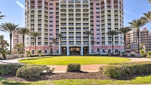 A large, multi-story hotel with a central courtyard, surrounded by palm trees and a well-maintained lawn. - Sunny Hammock Beach Condo: Balcony w/ Ocean Views! (Palm Coast)