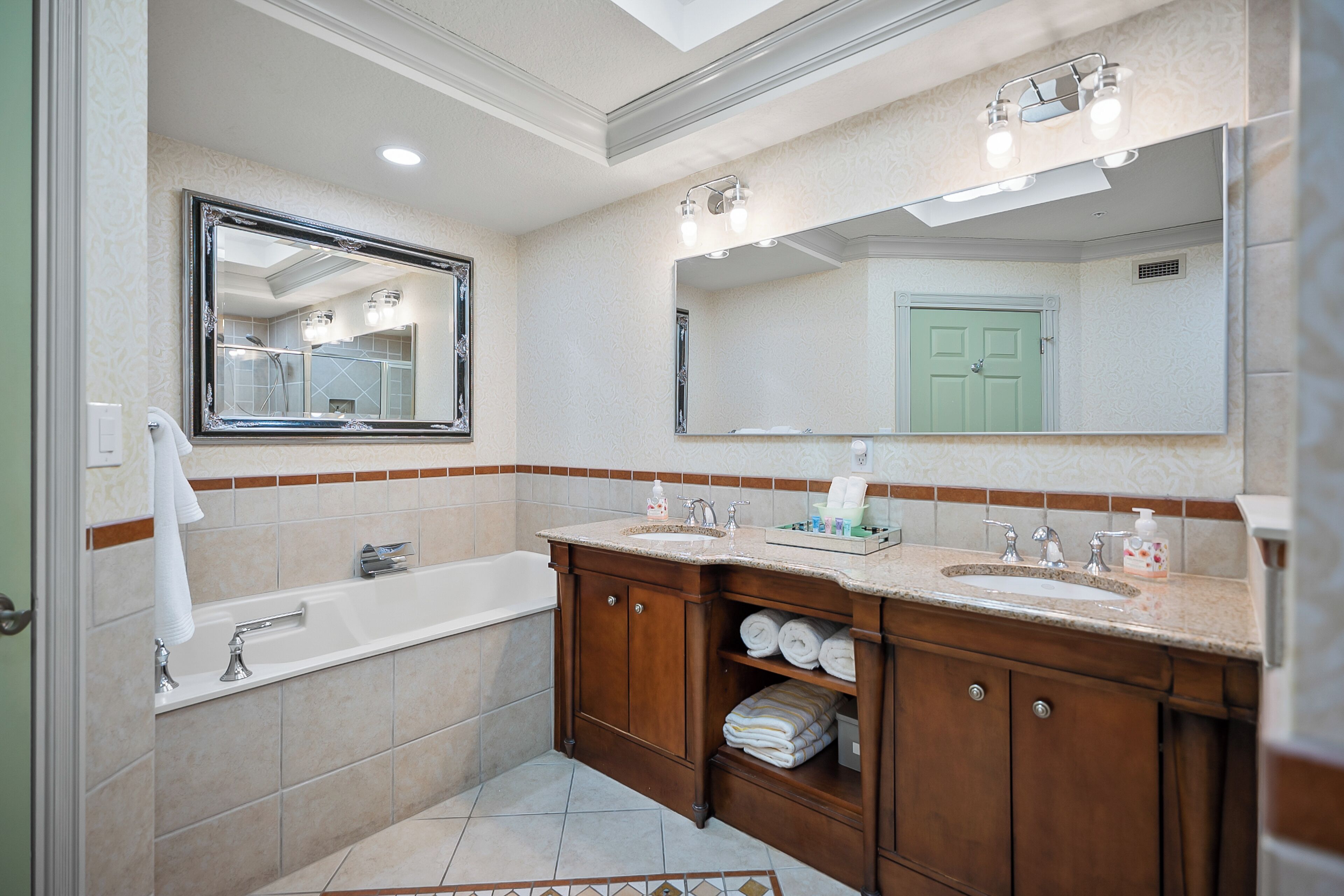 A modern bathroom with a bathtub, two sinks, and a vanity with shelves.