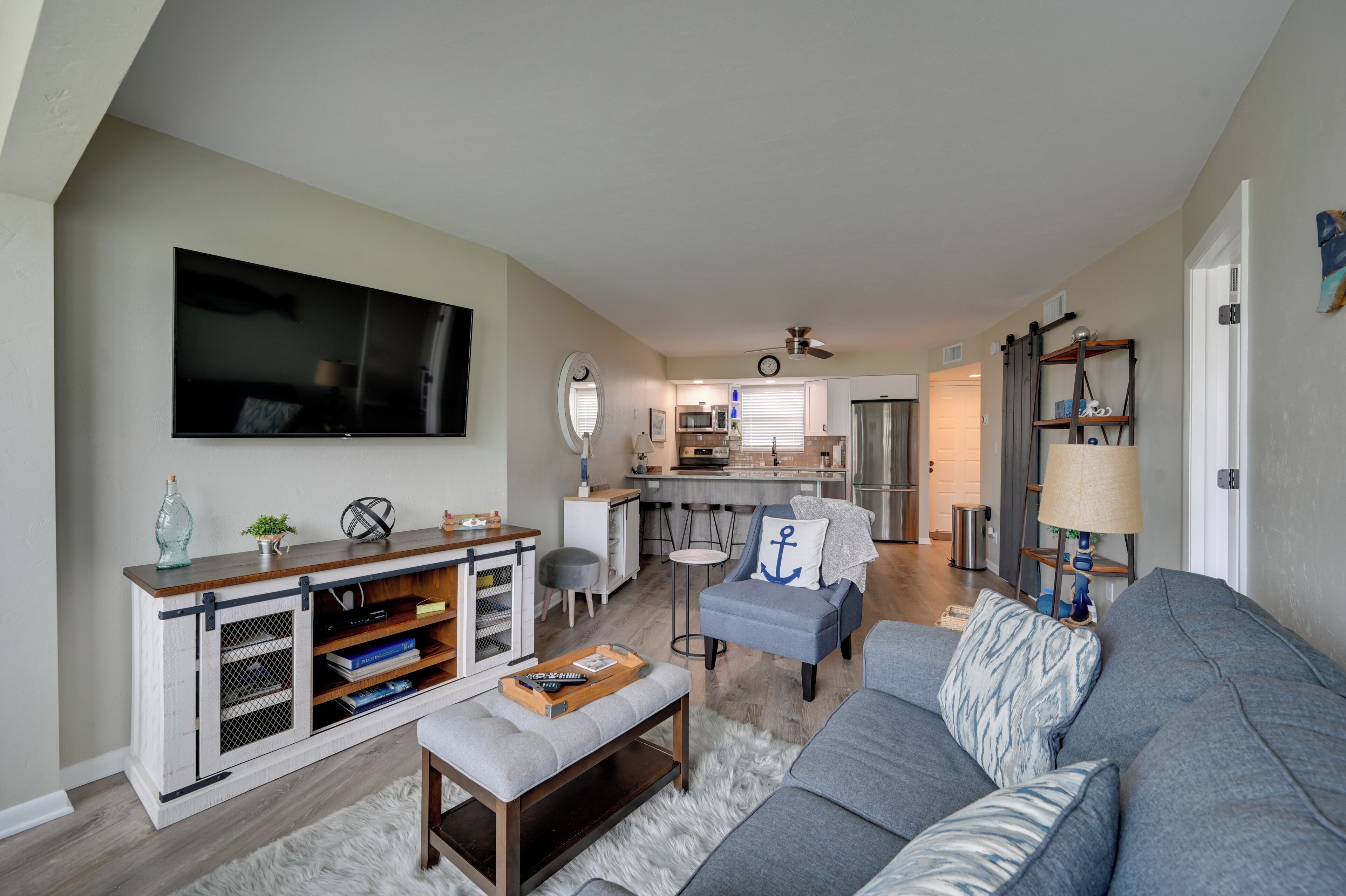 A modern living room with a grey sofa, a coffee table, and a TV mounted on the wall.