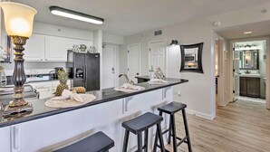 A modern kitchen with white cabinets, a black countertop, and a large island with stools.