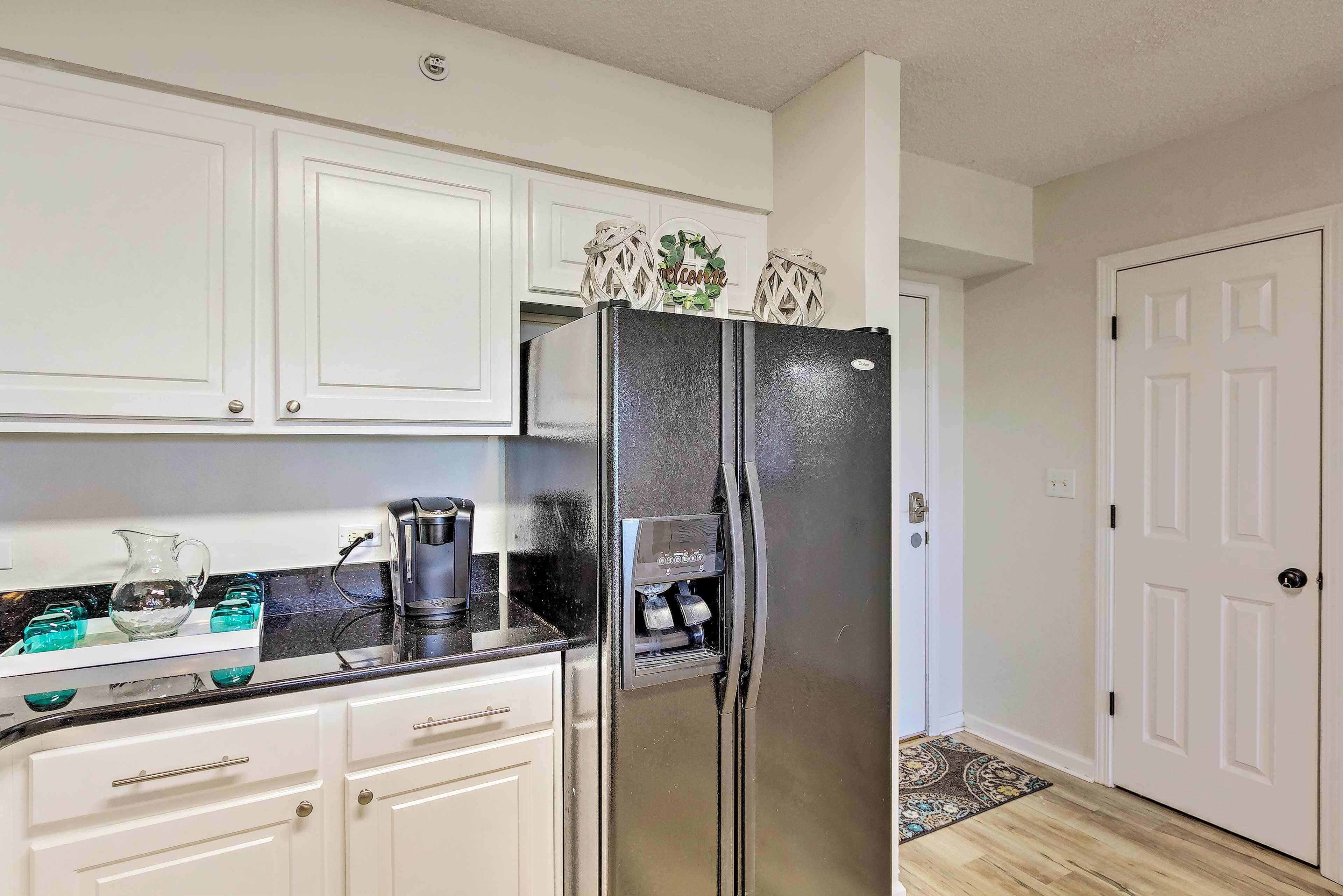 A kitchen with white cabinets, a stainless steel refrigerator, a coffee maker, and a water dispenser.