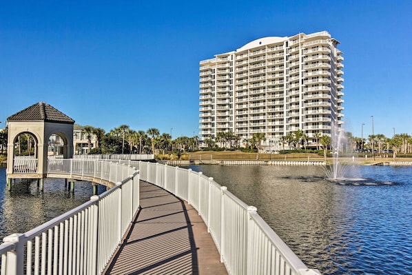 A waterfront promenade with a white fence, a small gazebo, and a large hotel in the background.