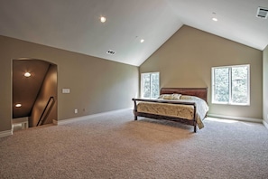 A bedroom with a large bed, a sloped ceiling, and two windows. - Roomy Home w/ Deck, 5 Mi to Lake Arrowhead Village (Lake Arrowhead)