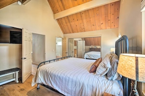 A bedroom with a bed, bedside table, lamp, and a wooden ceiling. - Lake Arrowhead Cabin w/ Balcony, Near Trails (Lake Arrowhead)