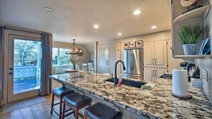 A kitchen with a large island, stainless steel appliances, and a view to the outside.