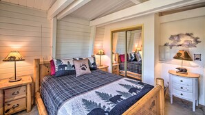 A cozy bedroom with a large bed, wooden headboard, two bedside tables with lamps, a dresser, and a mirror.