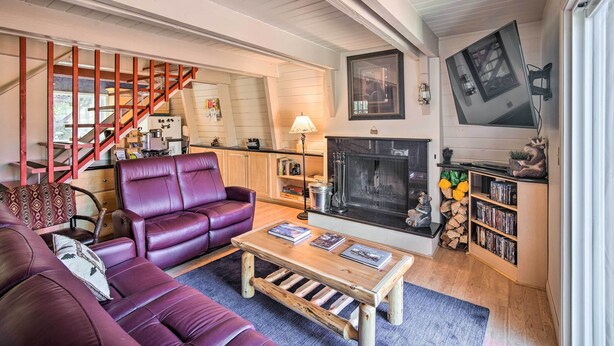 A living room with a sofa, coffee table, fireplace, bookshelf, and a staircase.