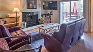 A living room with a fireplace, a television, and a balcony with outdoor furniture.