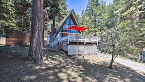 A cabin with a deck, surrounded by trees.