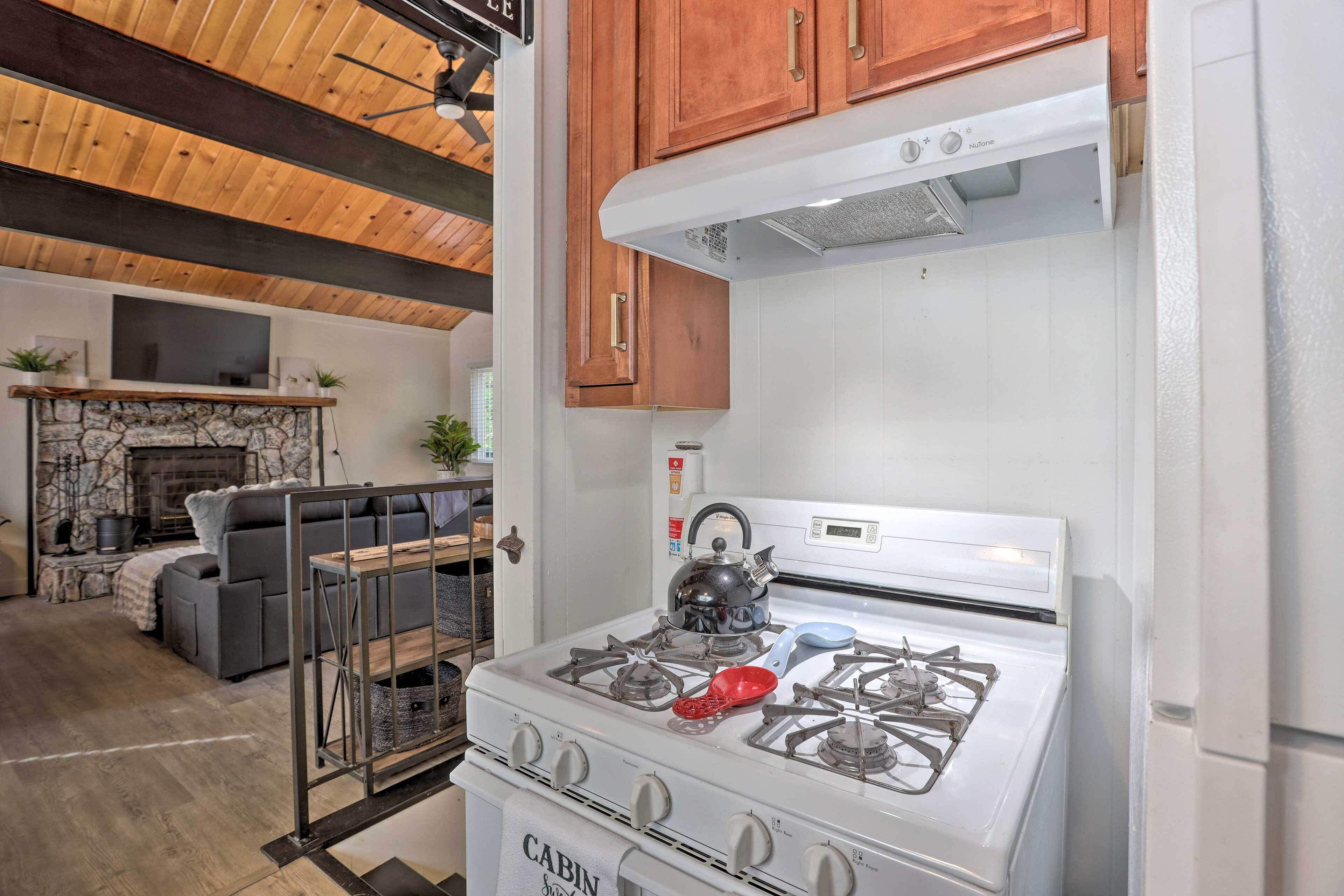 A kitchen with a white stove, wooden cabinets, and a stone fireplace.