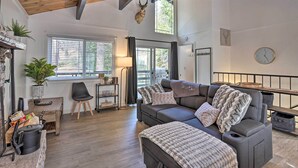 A cozy living room with a grey sofa, a wooden ceiling, and a mounted animal head.