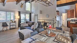 A spacious living room with a large sofa, a dining table with wooden chairs, and a kitchen area with wooden cabinets and a microwave.