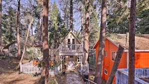 A cabin with a balcony, surrounded by tall trees and a white picket fence. - Cozy, Pet-friendly Mtn Cabin: 1 Mi to Lake Gregory (Crestline)