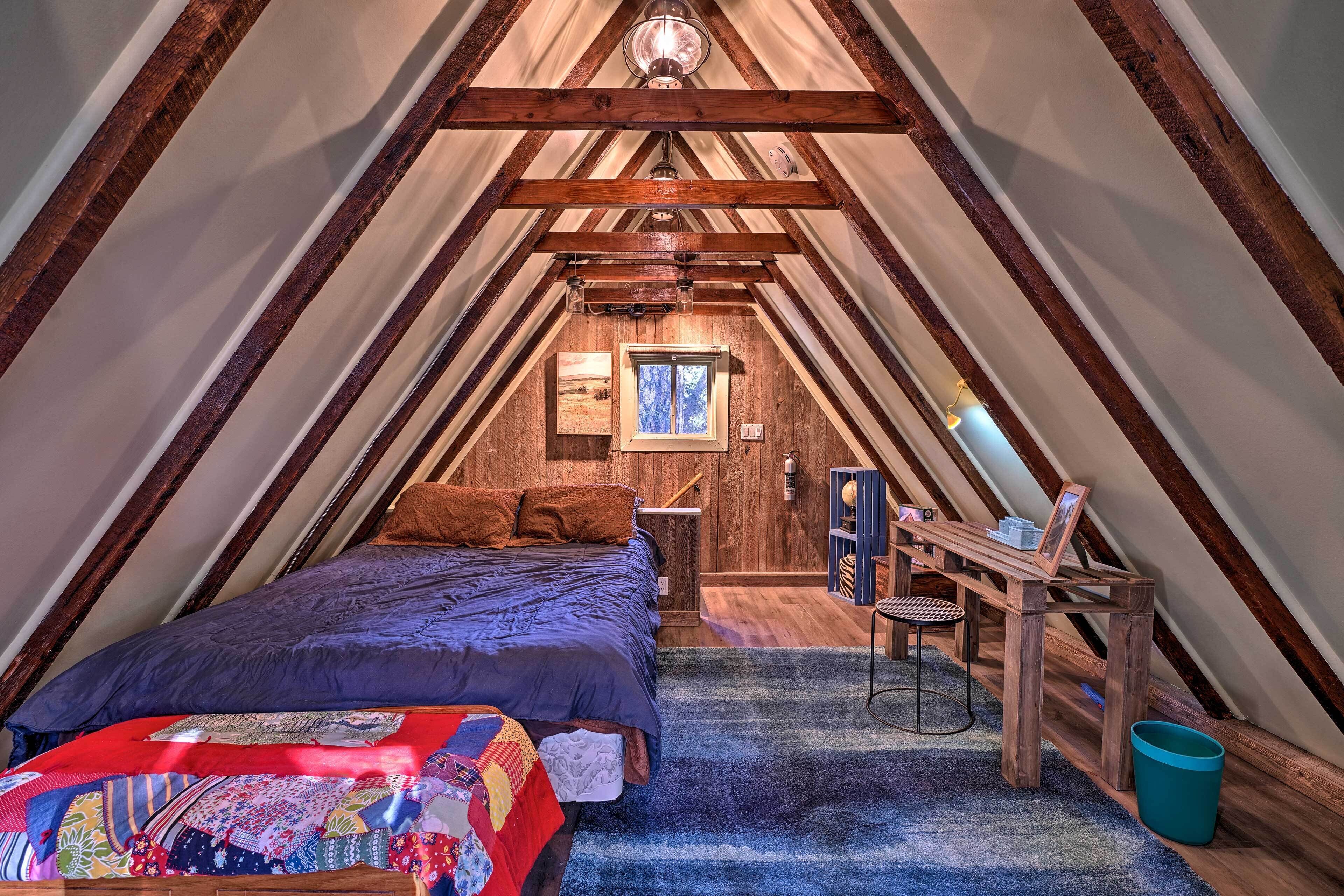 A cozy attic bedroom with a bed, a desk, and a chair.