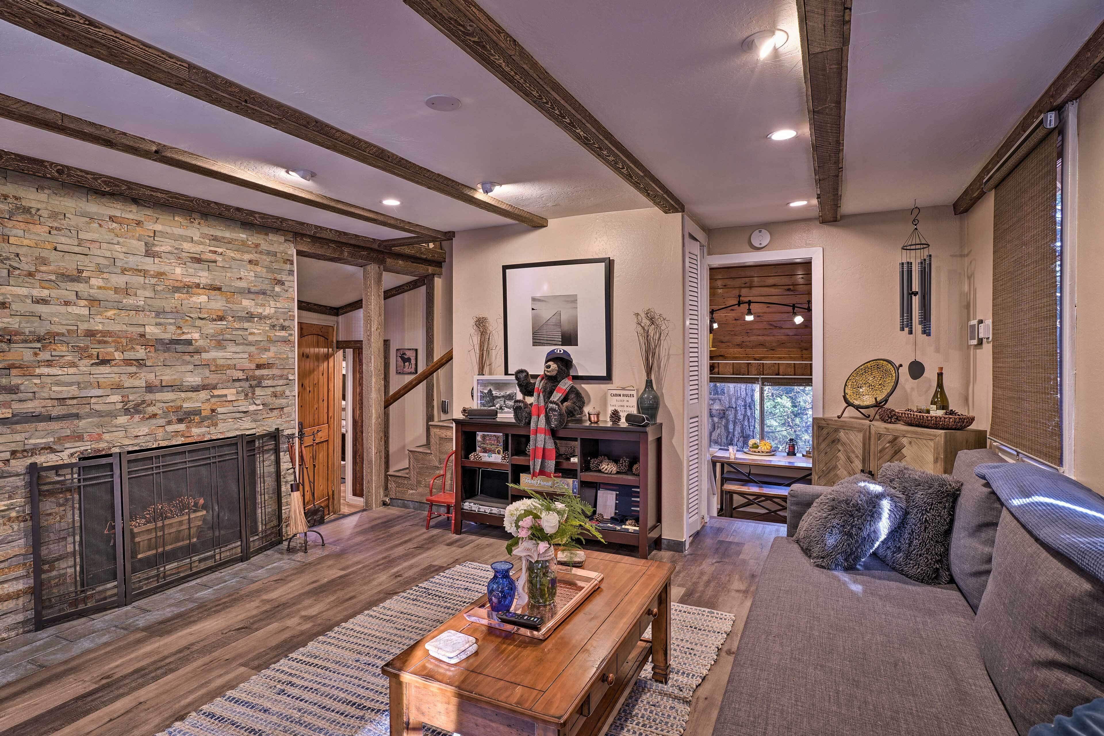 A cozy living room with a stone fireplace, a wooden coffee table, and a comfortable sofa.