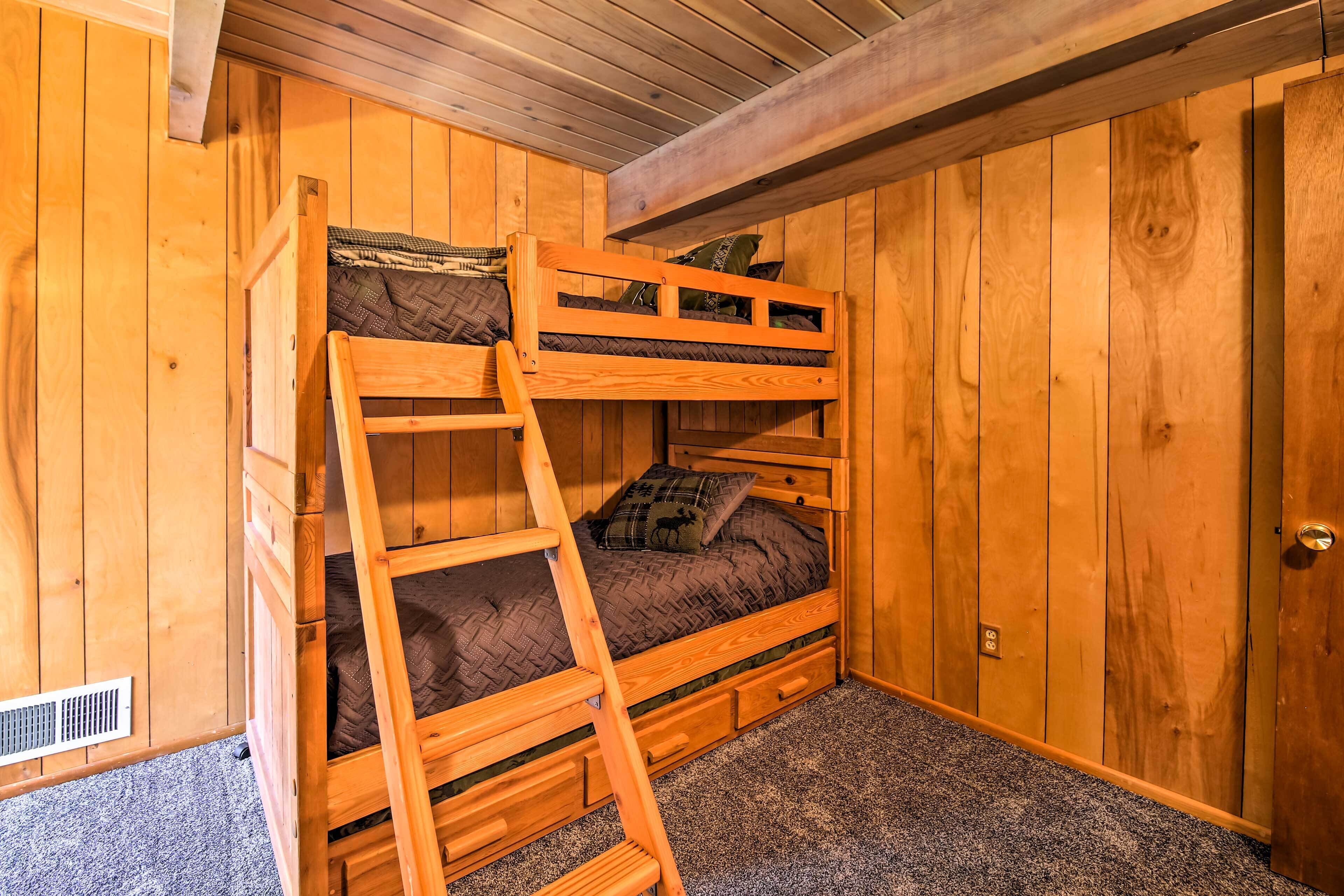 A bunk bed with a ladder, wooden walls, and a carpeted floor.