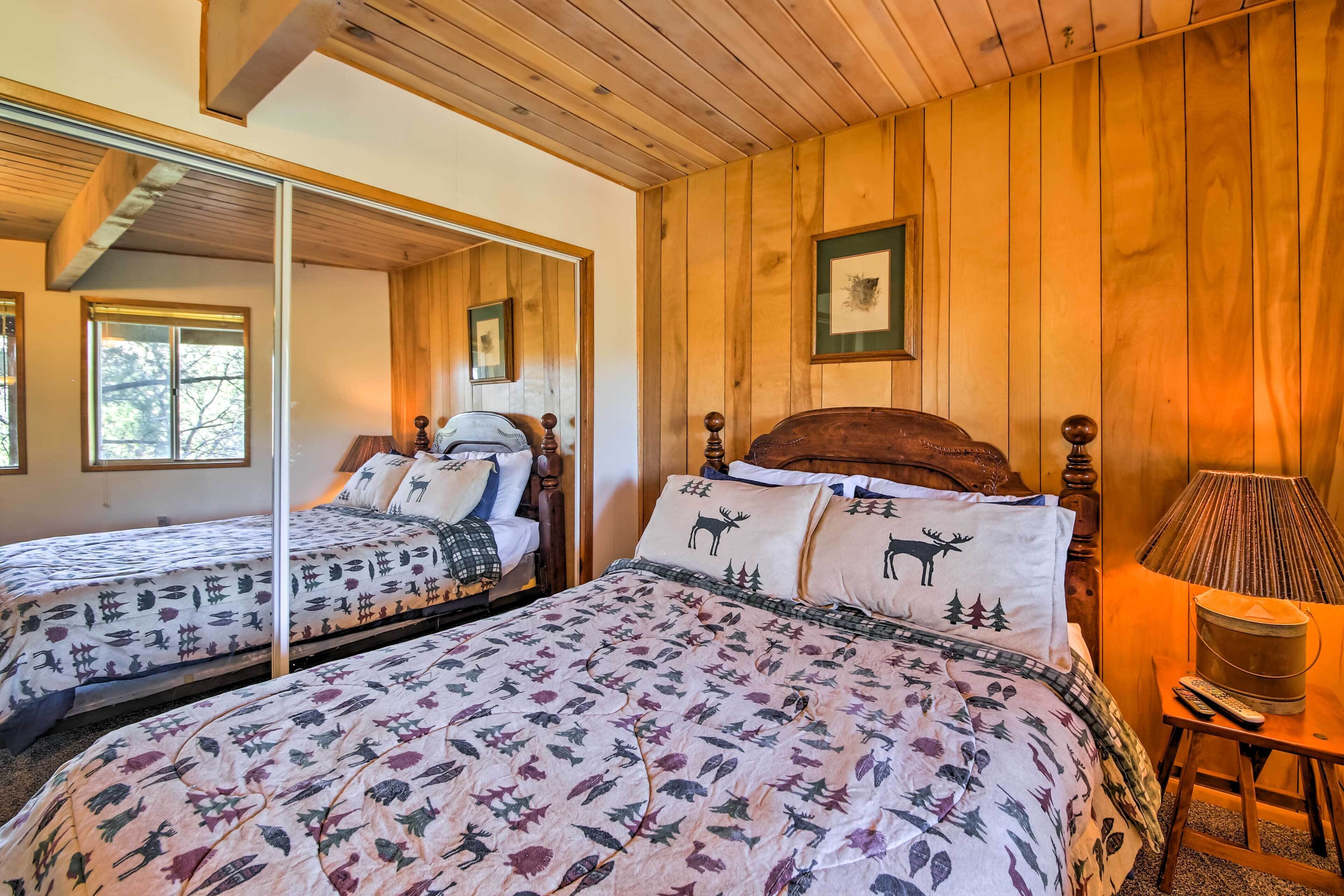 Una habitación con paneles de madera y dos camas, cada una con ropa de cama estampada y un espejo.