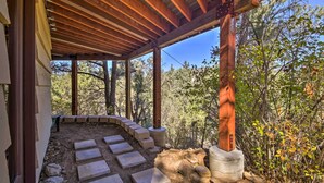 A covered outdoor area with a wooden pergola, stone steps leading to a seating area, and a view of surrounding trees. - 5 Mi to Big Bear Mtn Resort: Cozy Cabin w/ Deck (Big Bear City)